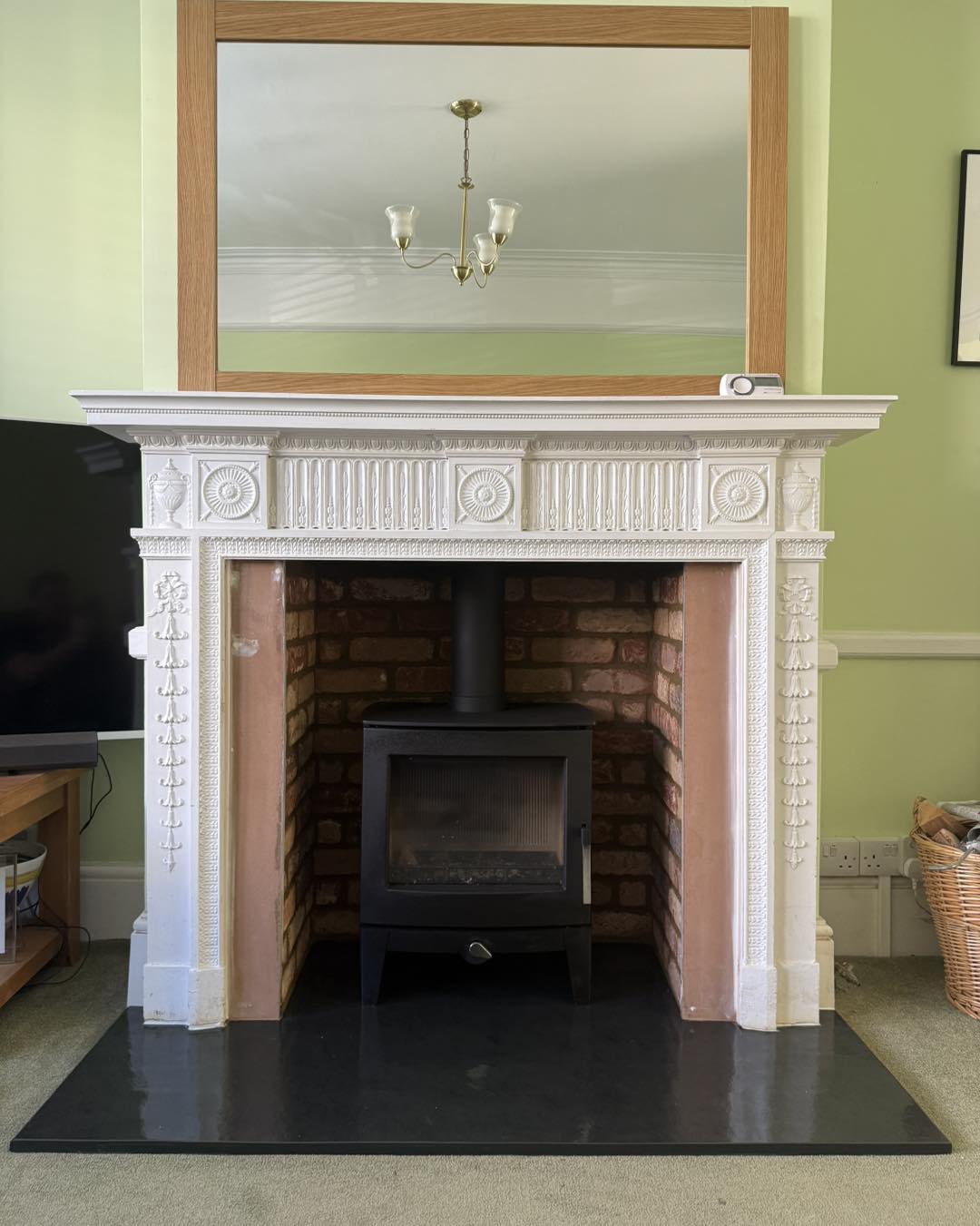 Period decorative fireplace surround with wood stove on slate hearth
